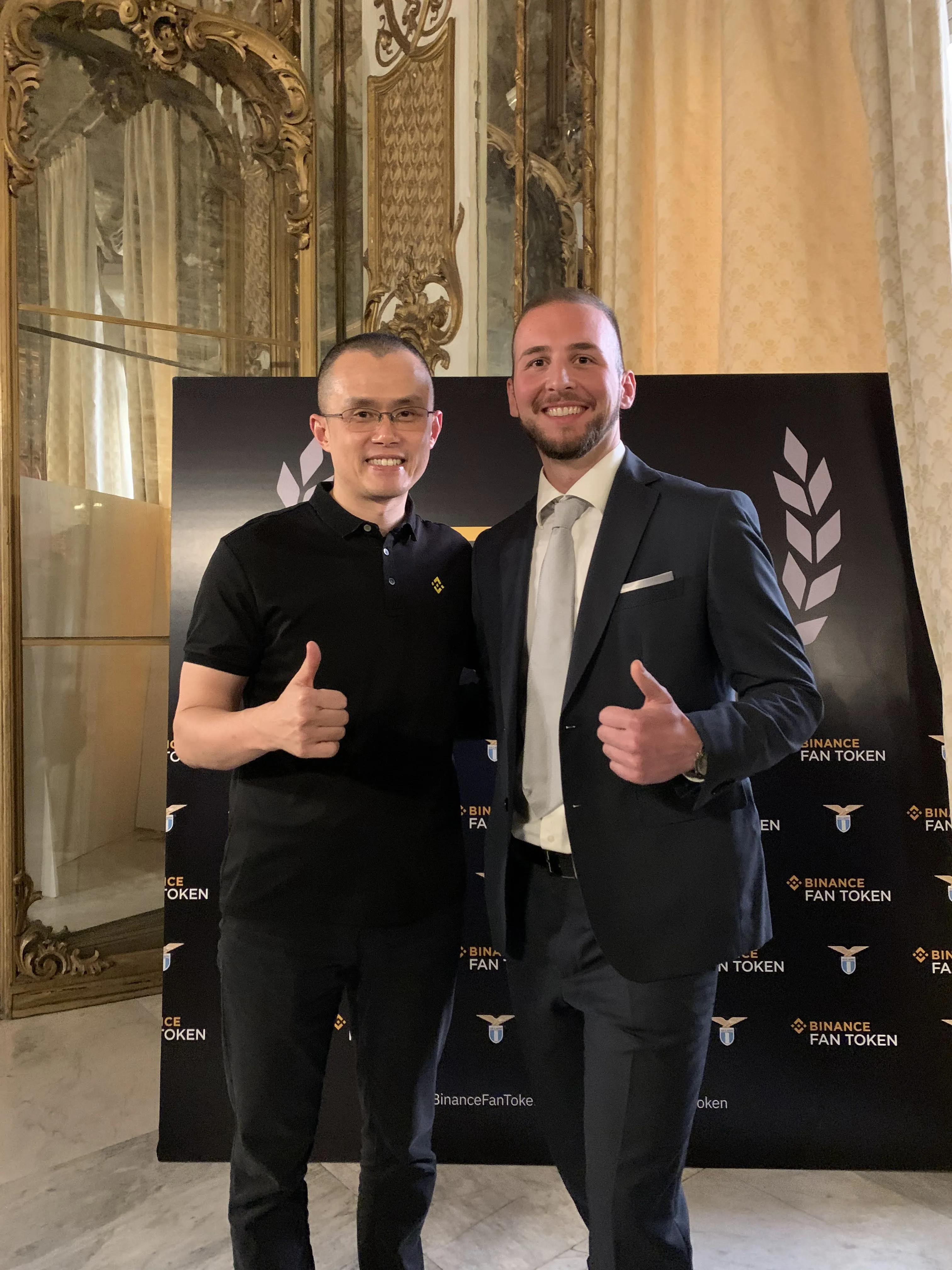 Matteo Fabrizi con Changpeng Zhao (CZ), fondatore di Binance, a CZ Meet Italy durante la Blockchain Week di Roma, davanti a un fondale con il logo Binance Fan Token.