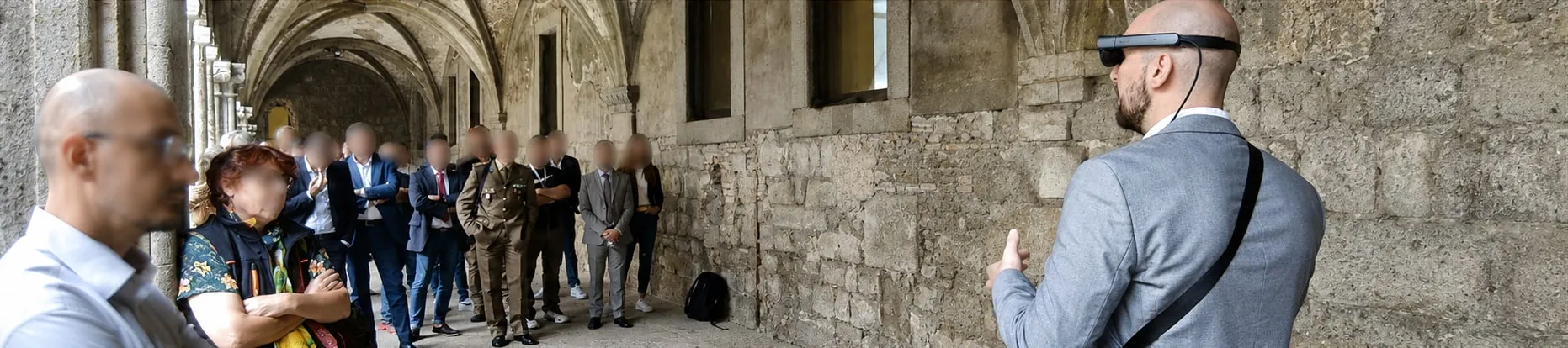 Matteo Fabrizi, wearing a Magic Leap 2 headset, presenting to a group of people along the cloister of Università della Tuscia.